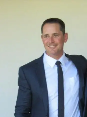 A man in a suit and tie smiling for the camera.